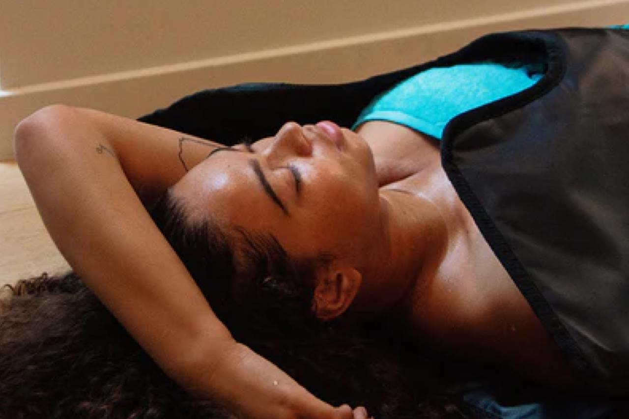 Woman sweating inside a sauna blanket during a sauna session