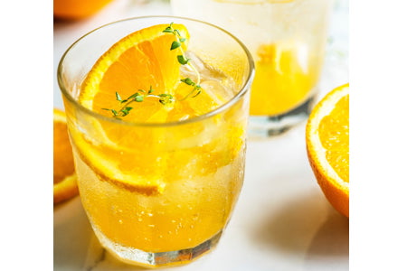 Non-alcoholic Citrus-Ginger Spritz sauna drink recipe with sparkling water, lemon juice, ginger, ice, and rosemary garnish in a glass