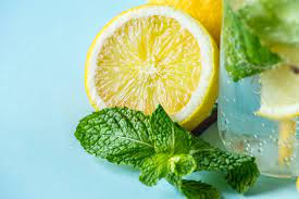 A glass pitcher of citrus mint refresh water with lemon, lime, orange slices, and fresh mint leaves, chilled and ready to hydrate during a sauna session.