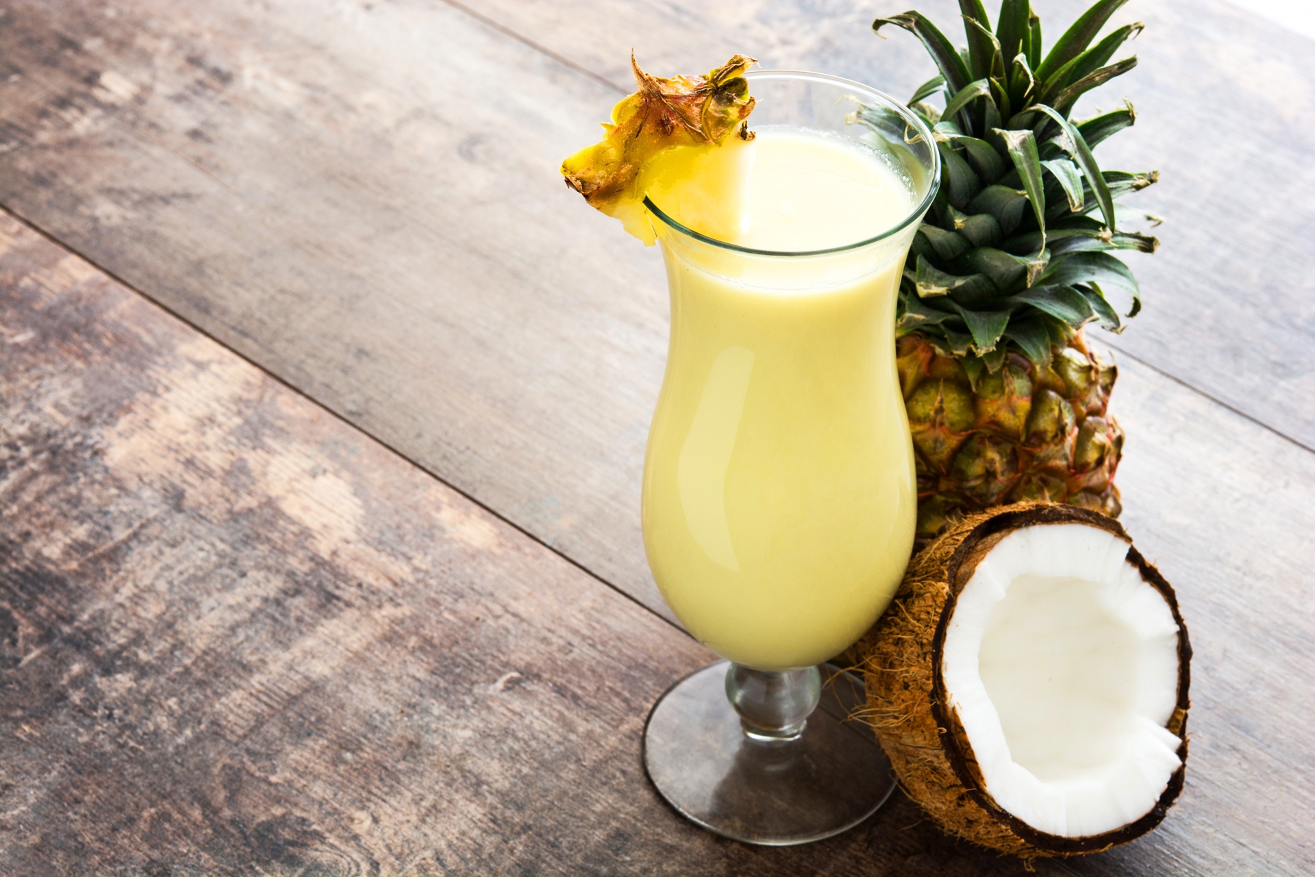 Fresh pineapple chunks and a coconut with a straw, ready for blending, illustrating the Coconut Pineapple Blend drink for post-sauna hydration.