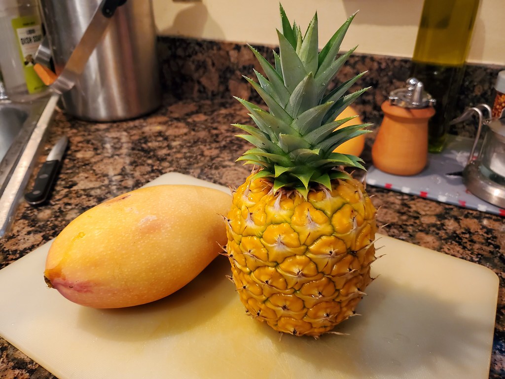 Fresh mango slices, pineapple arranged on a cutting board, ready for preparing sauna Citrus Tropical Twist infused water.