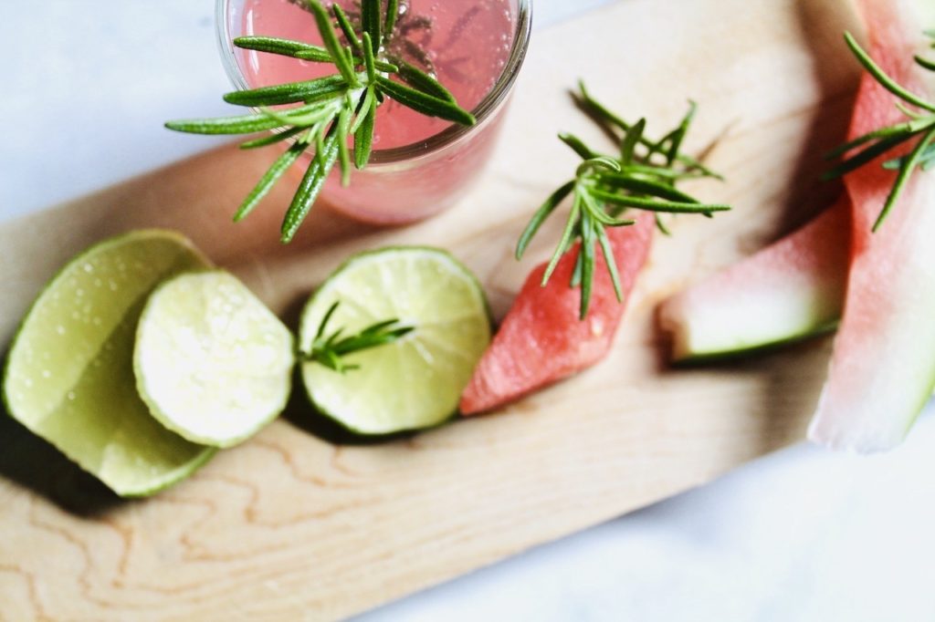 Fresh watermelon cubes and rosemary sprigs arranged on a cutting board, prepared for making the SaunaCe Watermelon Rosemary Quencher.
