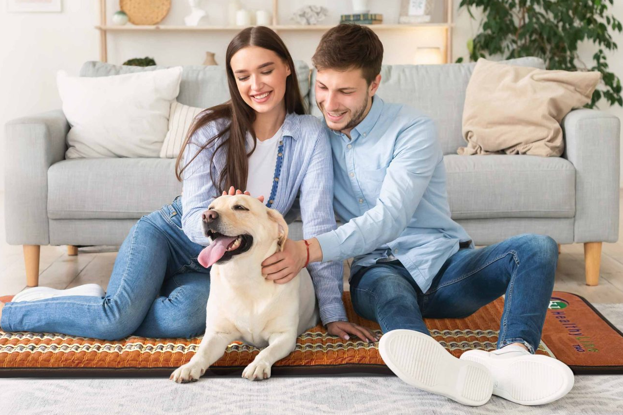 Young couple with dog sitting on HealthyLine TAO mat on the floor