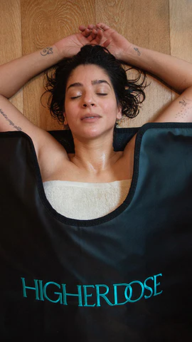 Woman in HigherDOSE sauna blanket for a detox session Woman in HigherDOSE sauna blanket for a detox session